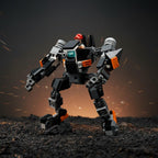 Assembled black, grey and orange mech robot build with a small red-helmeted minifigure seated in the cockpit, standing on dark gravel with glowing sparks