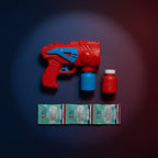 Flat lay of the red and blue bubble gun blaster with a spare solution bottle and three sealed refill sachets, dark spotlight background